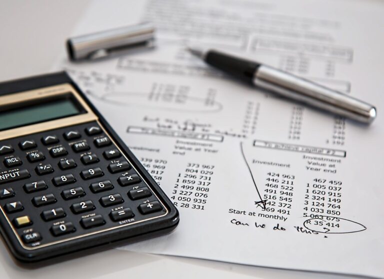 Calculator and pen on printed financial investment figures