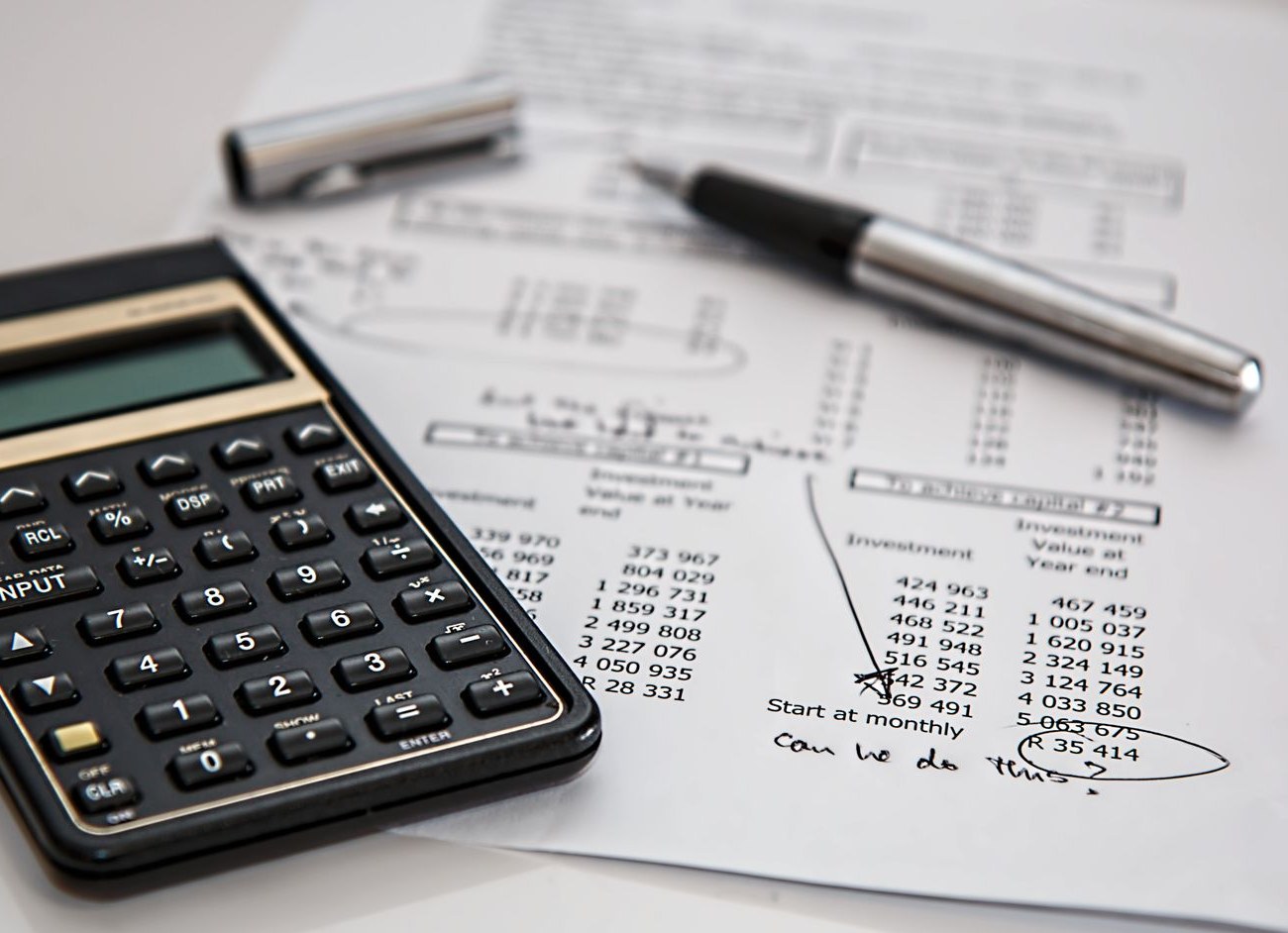 Calculator and pen on printed financial investment figures