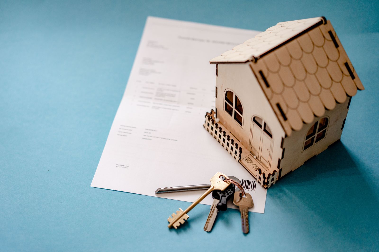 Wooden house model with keys on a property contract